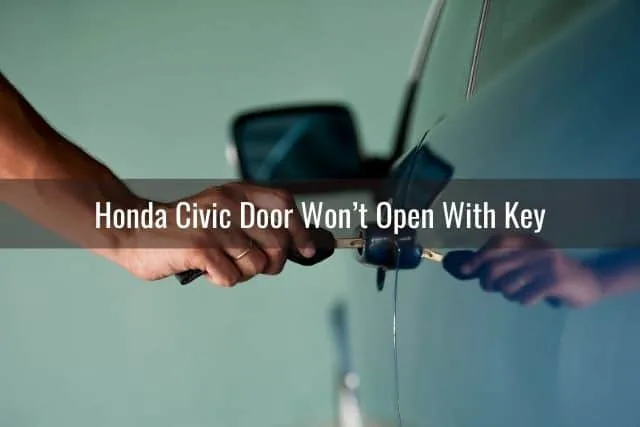 Hand putting car key into car door