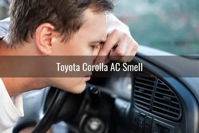 Guy holding nose because of bad smell coming from car AC vent