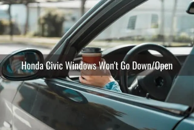 Open car window on drivers side with a hand holding a cup of coffee