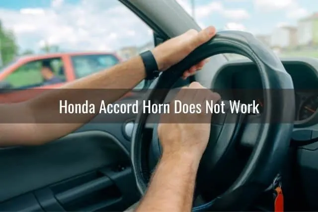 Hand on steering wheel and pressing car horn