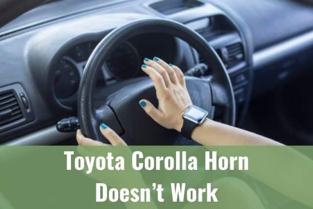 Female hand pushing car horn on steering wheel