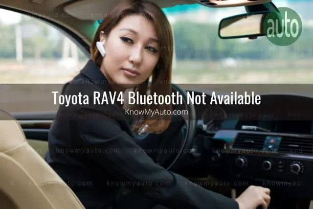 Asian female wearing bluetooth earpiece while looking back reversing in car